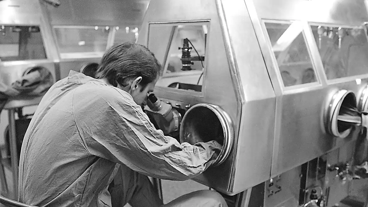 A scientist working at a biological safety cabinet with a microscope in a laboratory