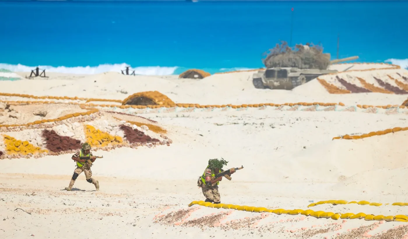 Camouflaged Egyptian soldiers moving across sandy ground during an exercise