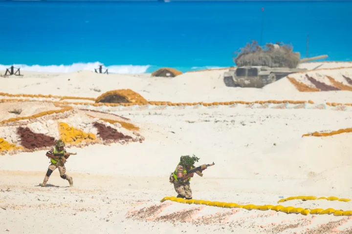 Camouflaged Egyptian soldiers moving across sandy ground during an exercise