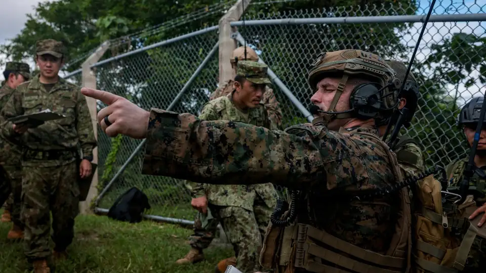 A U.S. Marine points out a target location as Japanese soldiers look on during dry close air support training at Camp Hansen, Okinawa