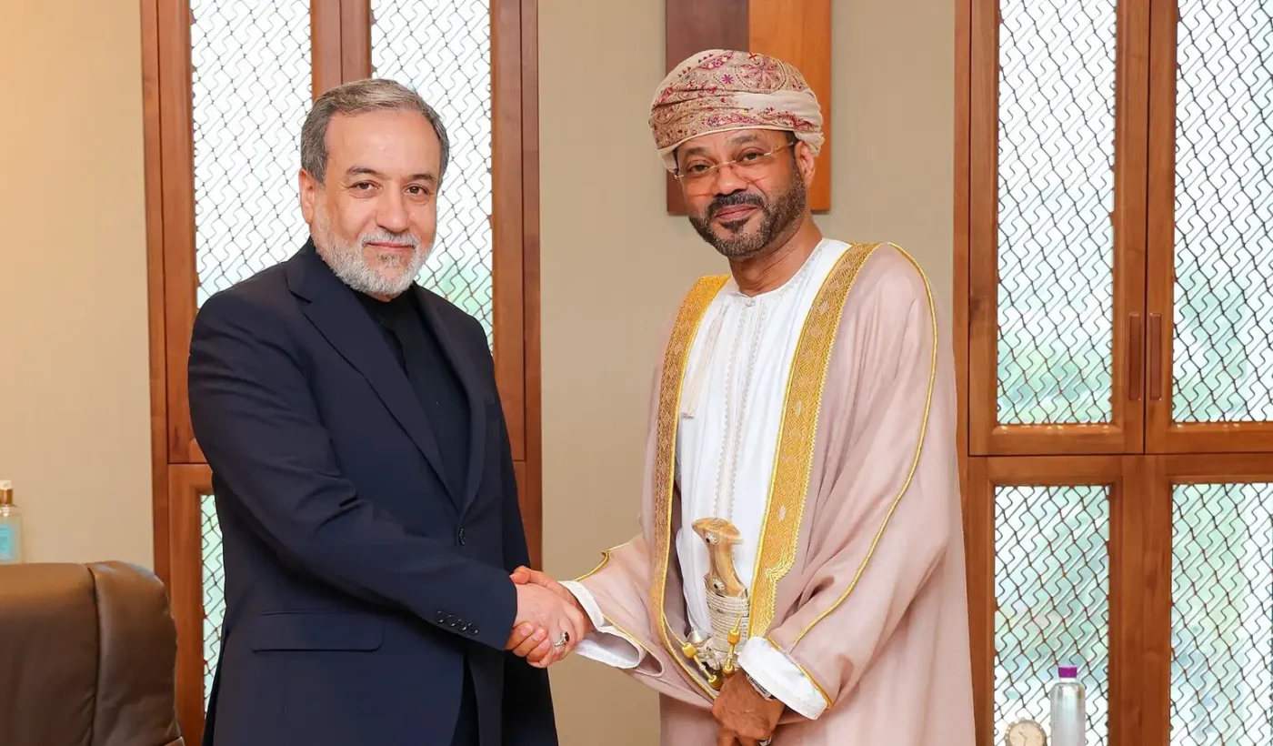 Iranian Foreign Minister Abbas Araghchi shaking hands with Omani Foreign Minister Sayyid Badr Albusaidi in an office in Muscat
