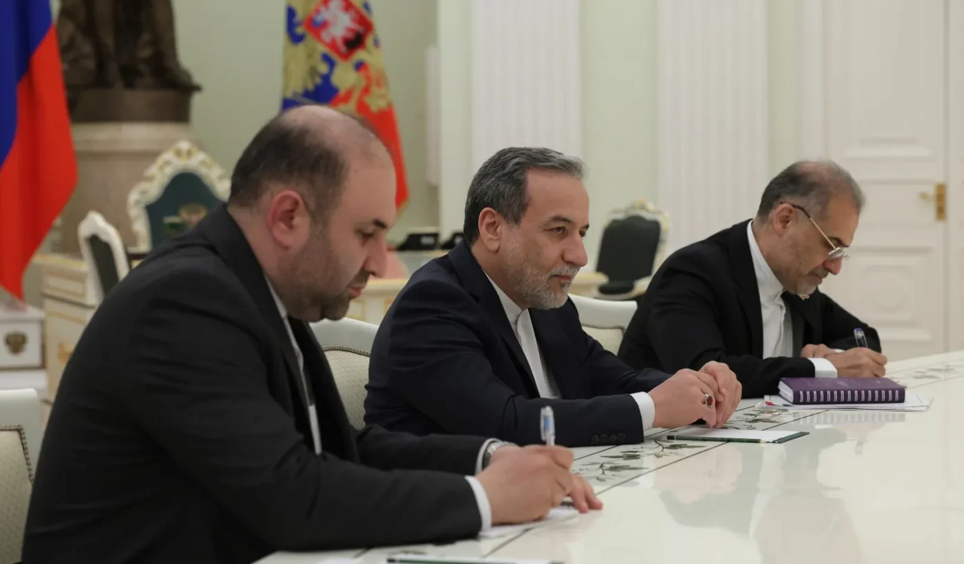 Abbas Araghchi in a dark suit seated at a negotiating table among members of a delegation