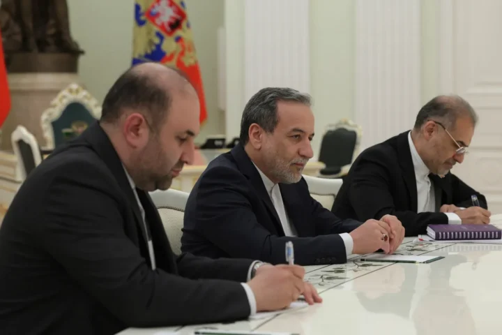 Abbas Araghchi in a dark suit seated at a negotiating table among members of a delegation