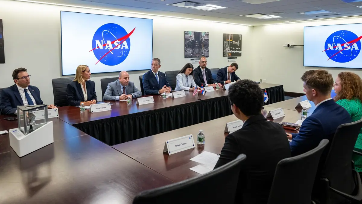 Officials sit around a conference table beneath NASA logo screens during a bilateral meeting after an Artemis Accords signing ceremony at NASA Headquarters