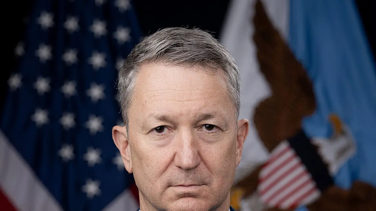 Official portrait of U.S. Air Force Gen. Dan Caine, chairman of the Joint Chiefs of Staff, in uniform in front of the U.S. and Department of War flags