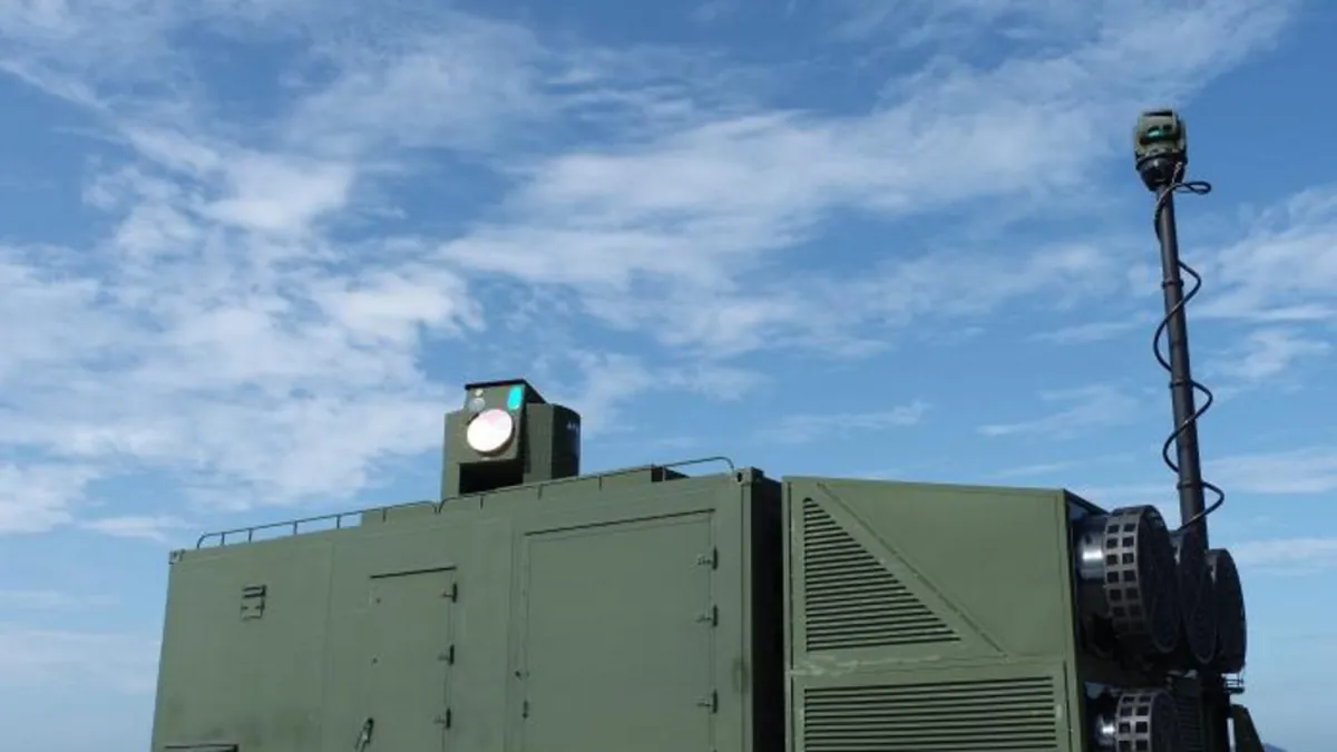 A containerised laser system with a beam director on the roof and a sensor mast