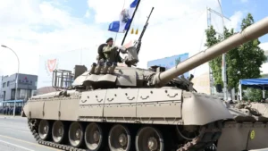 A Cyprus National Guard tank carrying a flag-bearer drives along a street during the military parade for the 66th anniversary of Cypriot independence