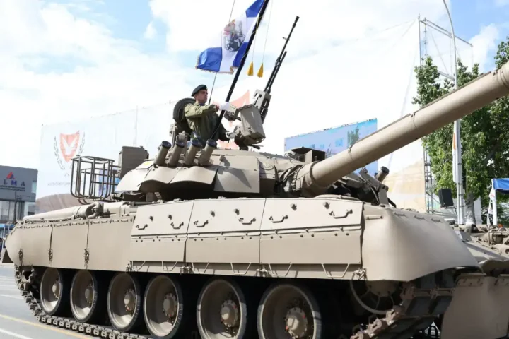 A Cyprus National Guard tank carrying a flag-bearer drives along a street during the military parade for the 66th anniversary of Cypriot independence