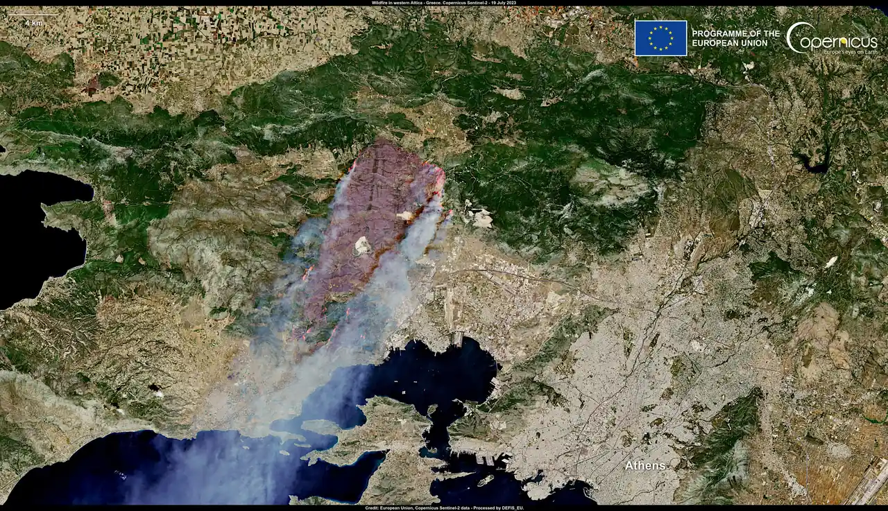 Satellite image of the burn scar and smoke plume of a wildfire in western Attica, with Athens at lower right
