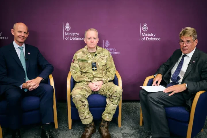 Three men seated in front of a Ministry of Defence backdrop at the DSEI UK 2027 theme launch