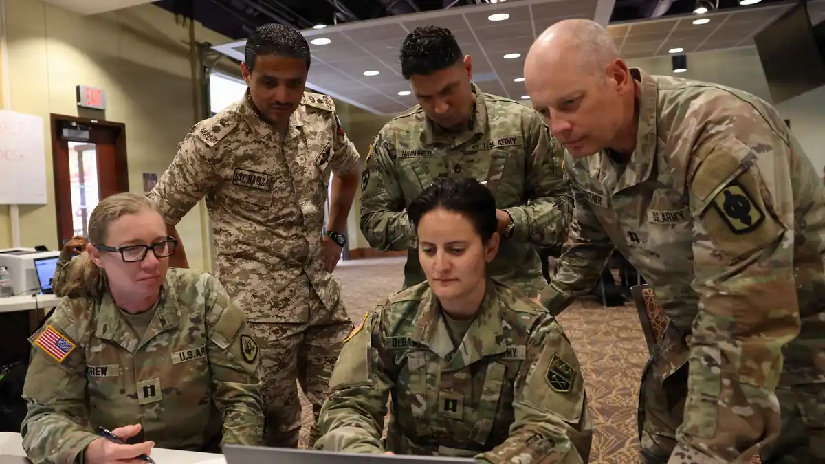 Army National Guard soldiers and a Jordanian Armed Forces officer gather around a laptop during a command post exercise at Fort Carson