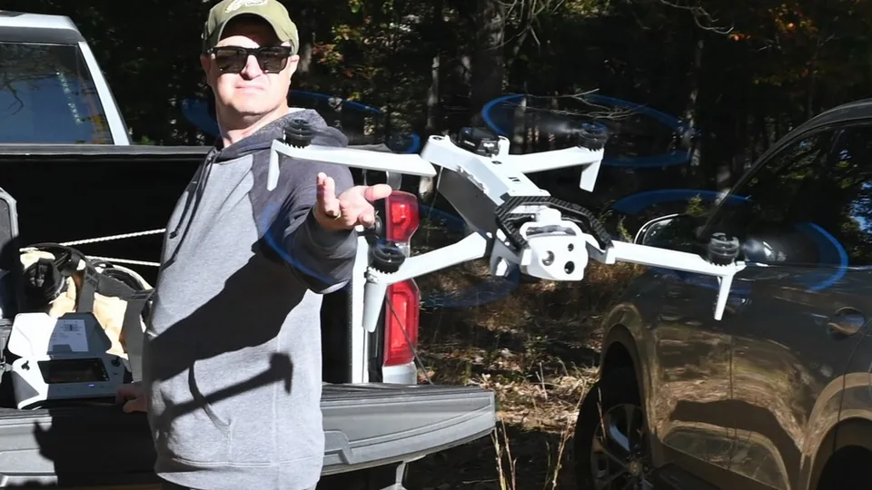 A trainer holding a quadcopter drone beside a pickup truck tailgate during a training exercise at Fort Indiantown Gap, Pennsylvania