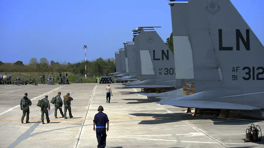 US Air Force F-15E Strike Eagle tails on the ramp at Andravida air base, with personnel walking
