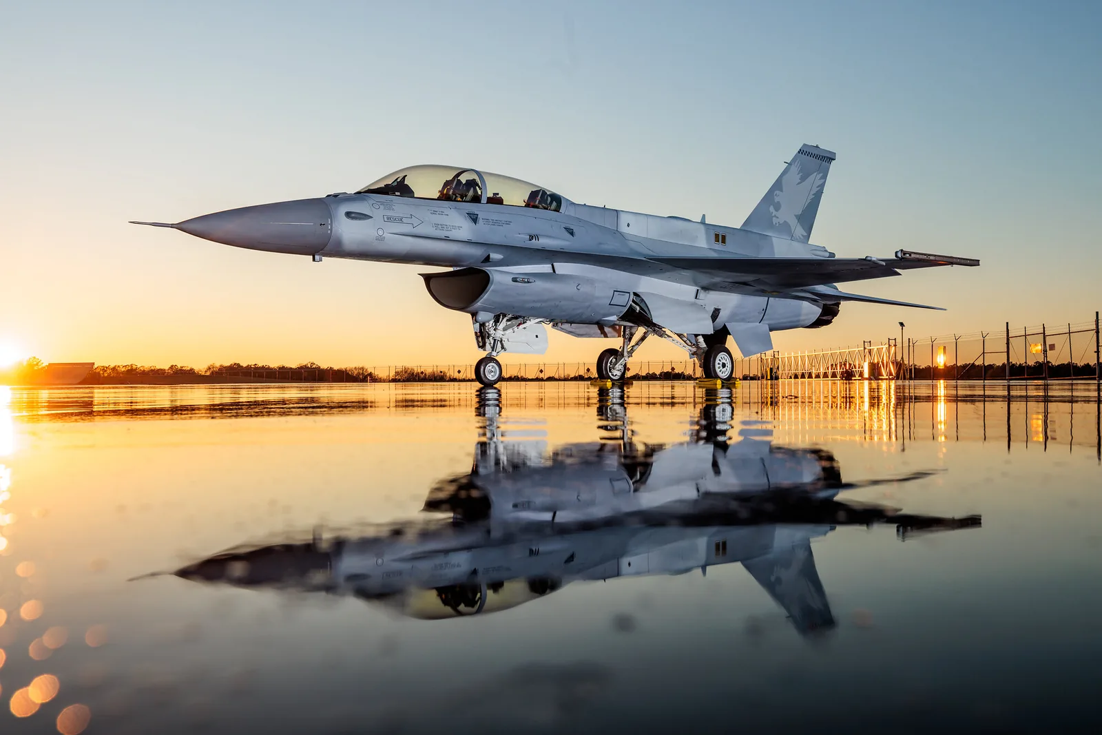 An F-16 Block 70 parked on the apron at Lockheed Martin’s Greenville, South Carolina site at sunset, reflected in standing water