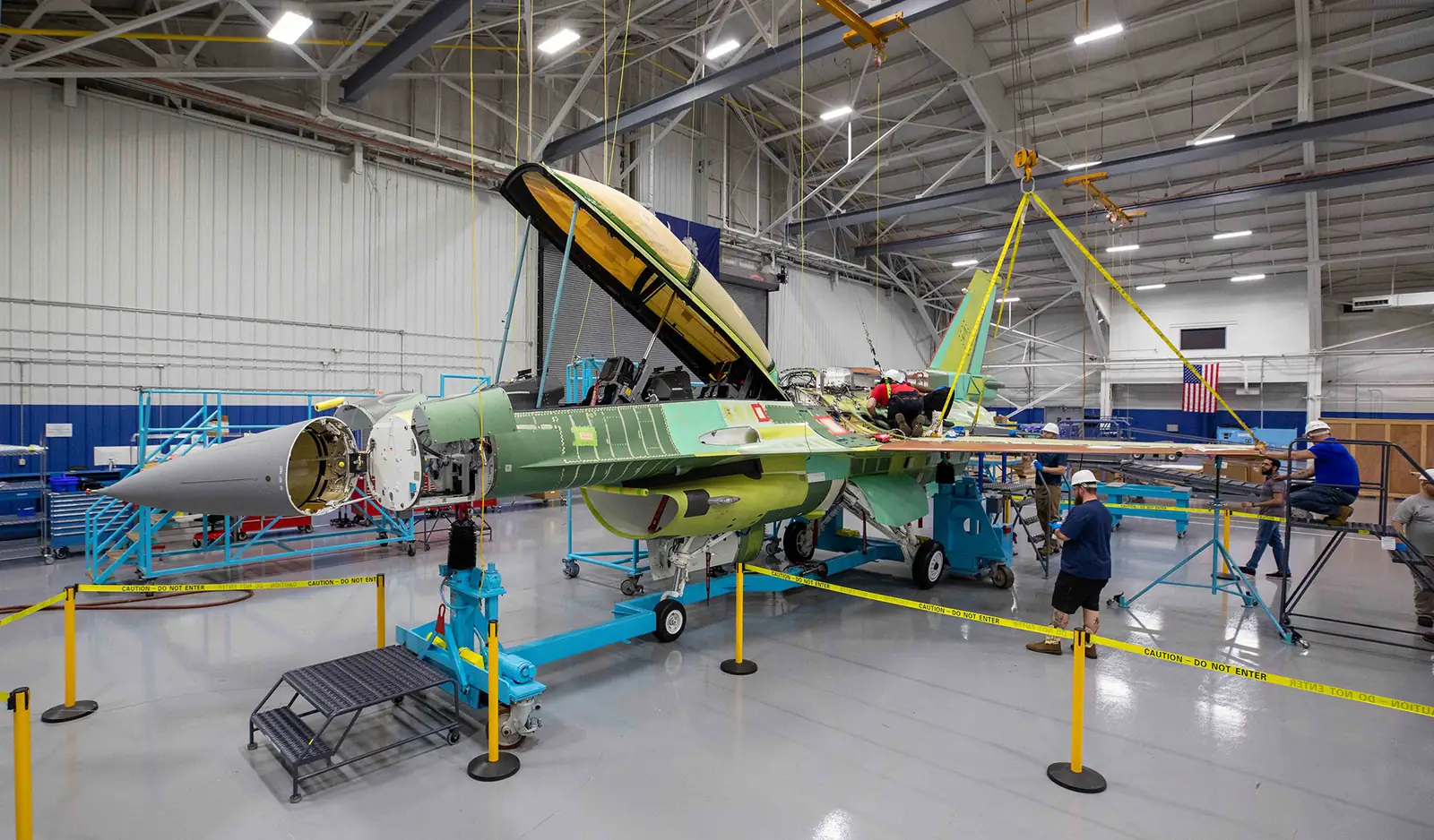 Technicians working around a partly assembled F-16 in its primer finish on the production line in Greenville, South Carolina