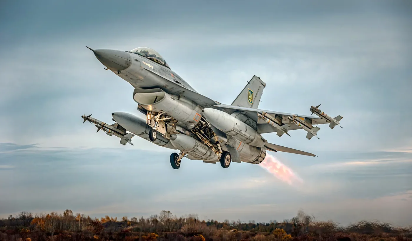 A grey F-16 fighter taking off with missiles on its wingtips