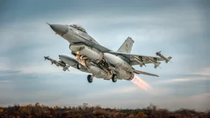 A grey F-16 fighter taking off with missiles on its wingtips
