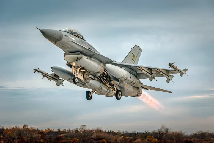 A grey F-16 fighter taking off with missiles on its wingtips