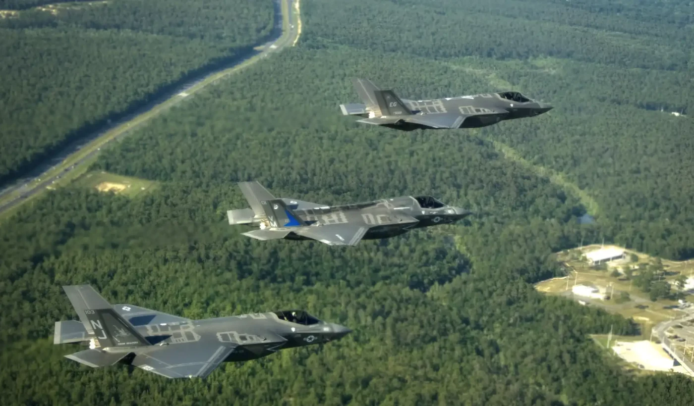 Three F-35 Lightning II fighters, an F-35A, an F-35B and an F-35C, flying in formation over forest near Eglin Air Force Base in Florida