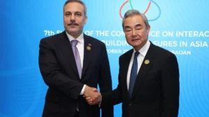Turkish Foreign Minister Hakan Fidan and Chinese Foreign Minister Wang Yi shake hands in front of a CICA summit backdrop in Baku