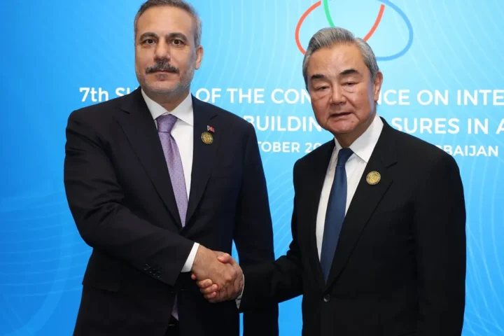 Turkish Foreign Minister Hakan Fidan and Chinese Foreign Minister Wang Yi shake hands in front of a CICA summit backdrop in Baku
