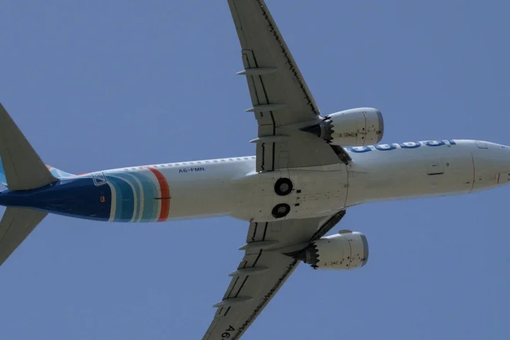 A flydubai Boeing 737 MAX 8 seen from below against a blue sky during take-off