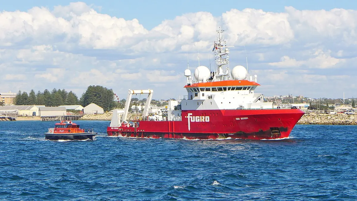 A white and orange research vessel leaving a harbour