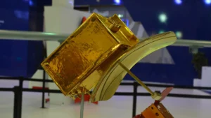 A gold-foil scale model of the Göktürk-3 radar satellite with its curved antenna reflector on a stand at the Turkish Aerospace booth