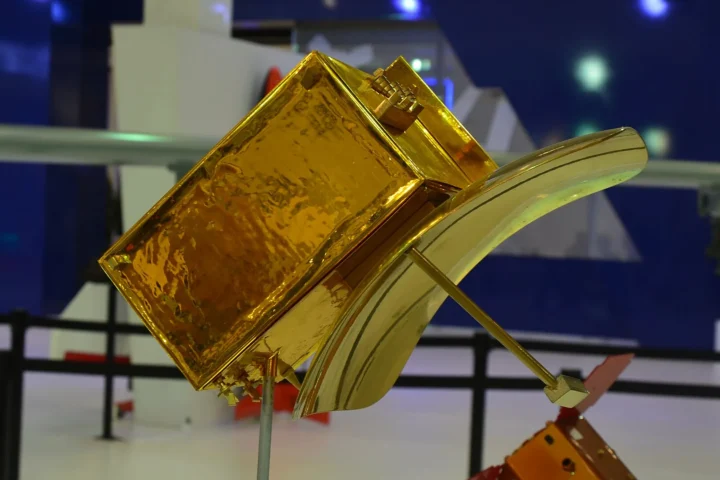 A gold-foil scale model of the Göktürk-3 radar satellite with its curved antenna reflector on a stand at the Turkish Aerospace booth