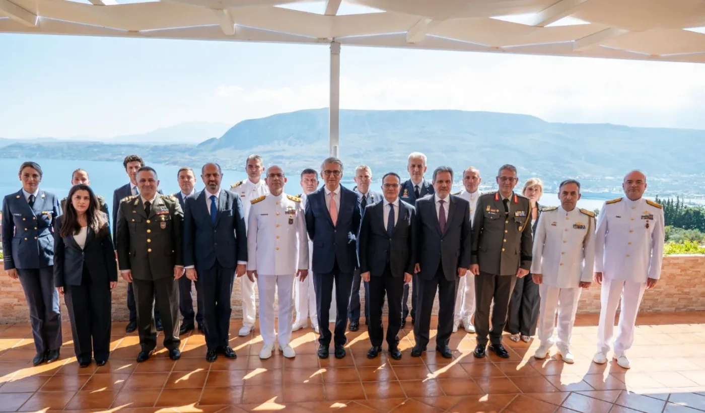 Group photo of military officers and diplomats from the Greek and Turkish delegations on a terrace overlooking the sea near Chania