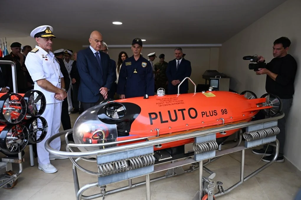 The Minister of National Defence with the Navy chief and an officer in front of an orange PLUTO PLUS underwater vehicle