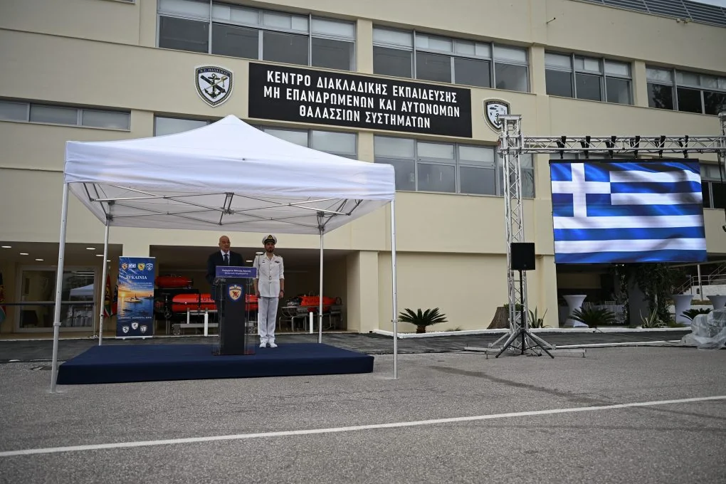 Nikos Dendias at a lectern under a white tent in front of the new training centre