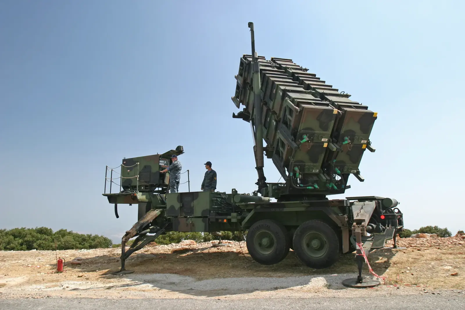 An M901 Patriot launcher of the Hellenic Air Force with its canisters raised, with two crew members beside it