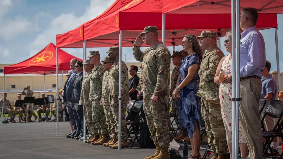 U.S. Army soldiers and guests stand at attention under red tents during the activation ceremony of an air defense battalion at Andersen Air Force Base, Guam