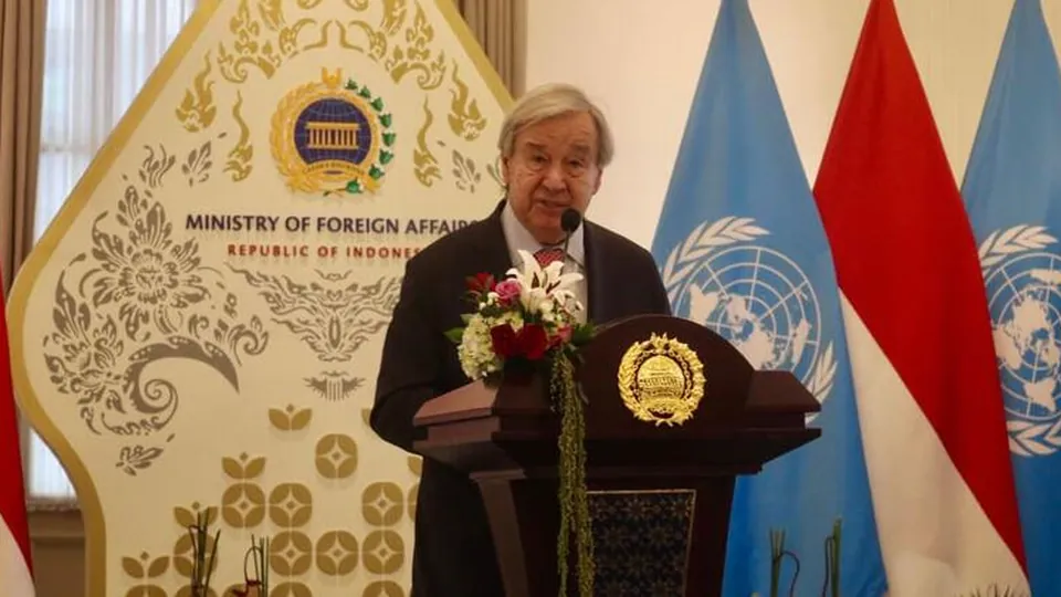 UN Secretary-General António Guterres speaking at a podium in front of UN and Indonesian flags at the Indonesian Ministry of Foreign Affairs in Jakarta