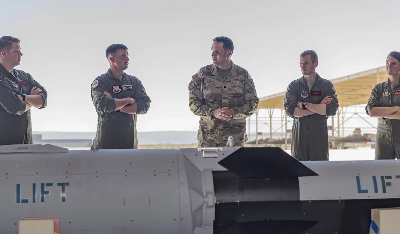 Air Force aircrew listen to a briefing beside a HACM test article at Edwards Air Force Base, California