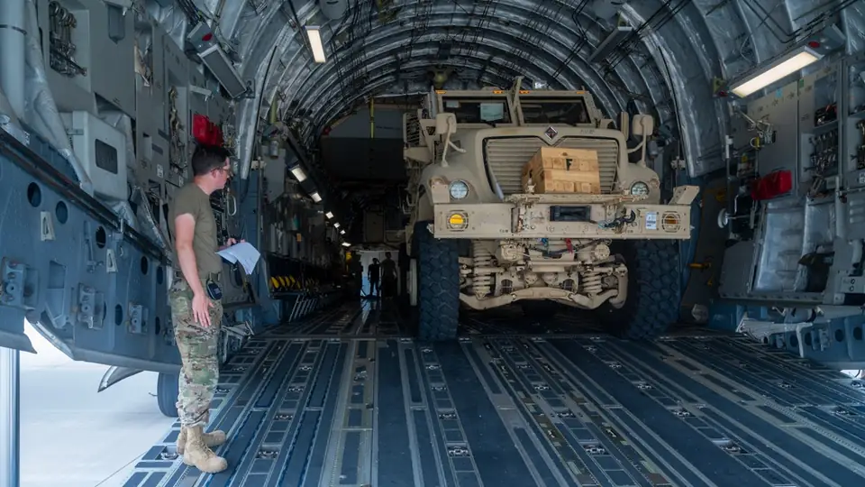 Airmen load an MRAP vehicle onto a C-17 transport aircraft at Pope Army Airfield for transport to Port-au-Prince, Haiti