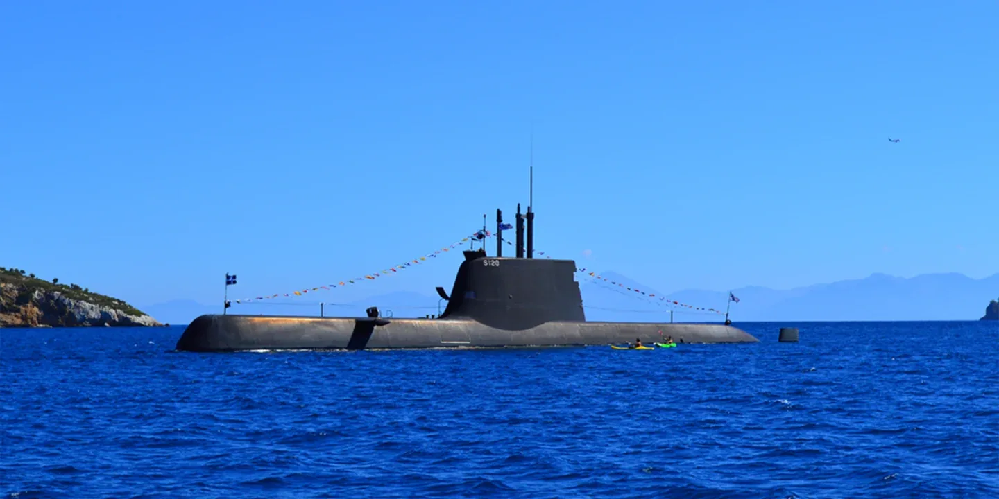 The Hellenic Navy submarine Papanikolis (S-120) on the surface at sea, with flags strung along its sail