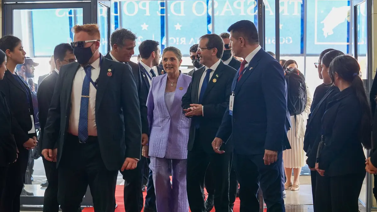 Israeli President Isaac Herzog and his wife Michal walking through a crowded entrance hall at a 2026 event in Costa Rica
