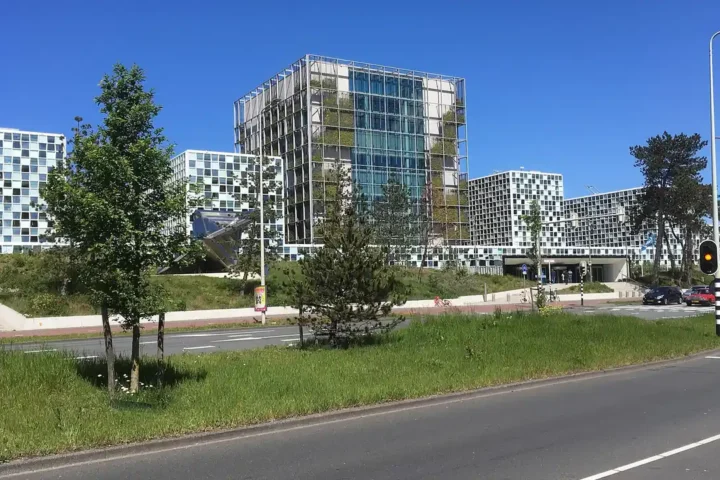 The International Criminal Court building in The Hague, a glass and steel complex under a blue sky