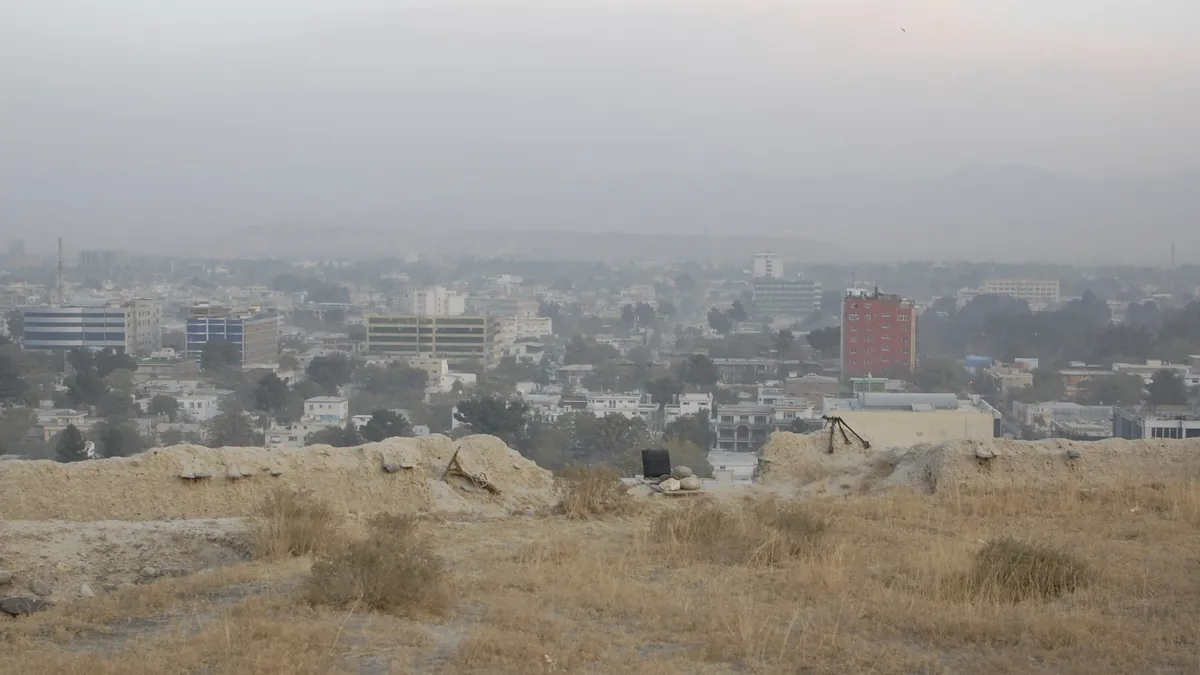 View over central Kabul with buildings and hills in haze, seen from a hilltop