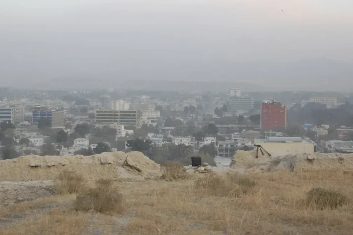 View over central Kabul with buildings and hills in haze, seen from a hilltop