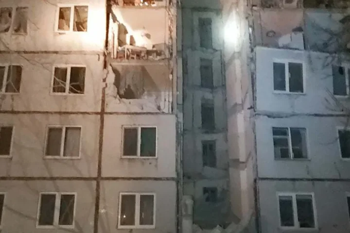 Night view of an apartment block in Kharkiv with damaged balconies and shattered windows