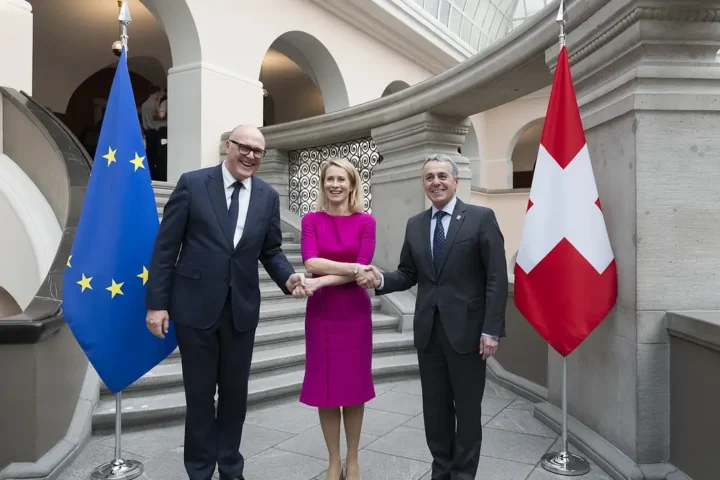 Kaja Kallas shaking hands with Swiss and EU officials in front of the EU and Swiss flags in Zurich
