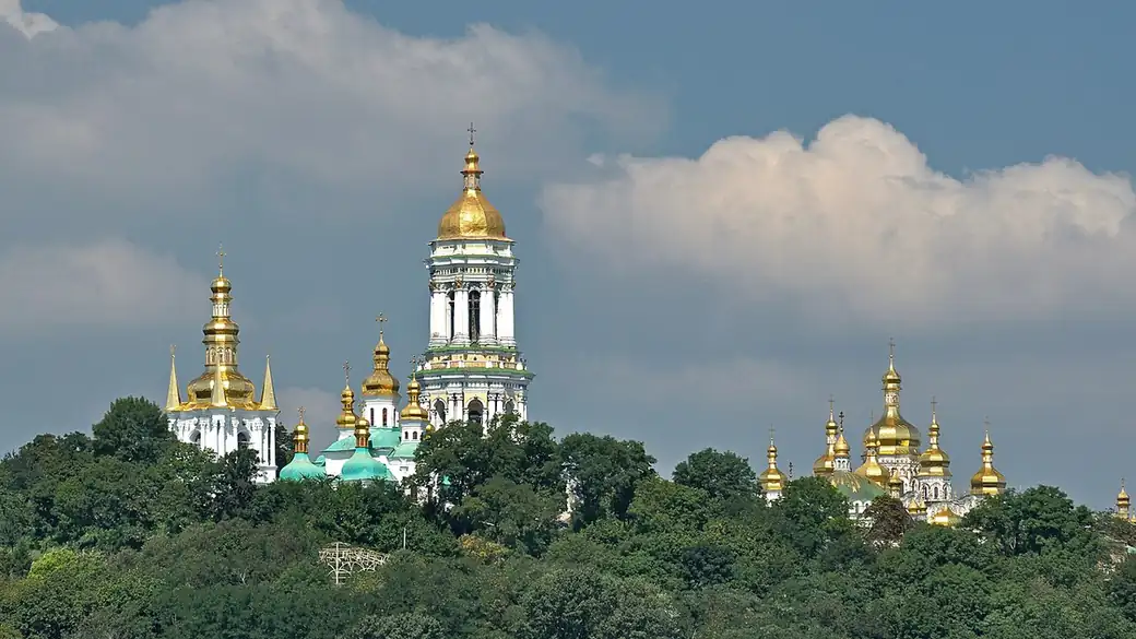 Golden domes and the Great Bell Tower of the Kyiv Pechersk Lavra above trees on the right bank of the Dnieper