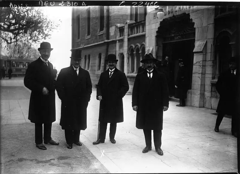 Four men in overcoats and hats stand outside the Hotel du Chateau d'Ouchy in Lausanne during the 1922 peace conference