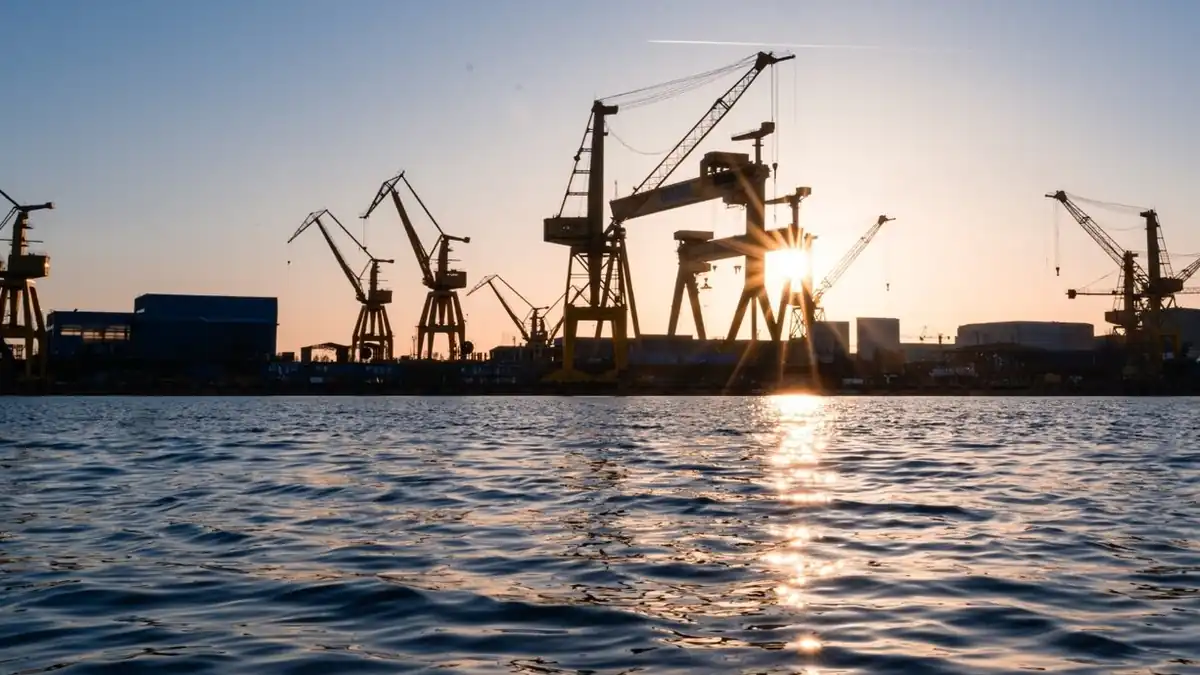 Shipyard cranes silhouetted against the sun over the water at the Mangalia shipyard