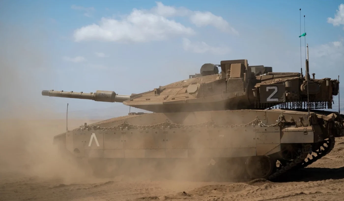 An Israeli Merkava Mk4 Barak main battle tank kicking up dust as it moves across open ground