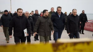 Kyriakos Mitsotakis and Volodymyr Zelensky walking in a port among members of the delegations
