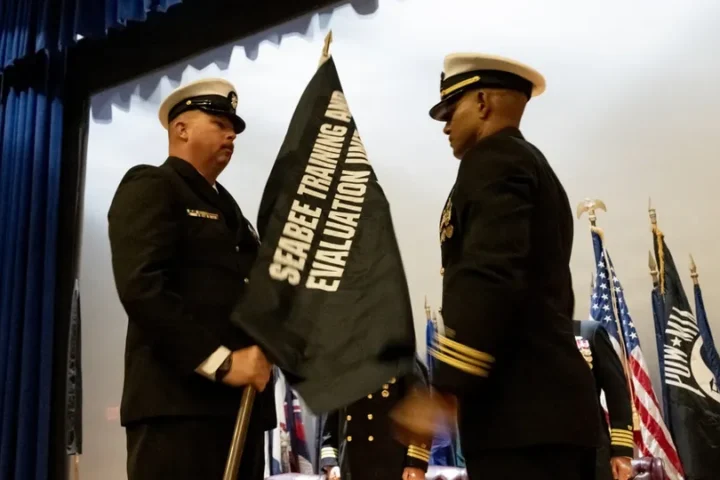 Seabee Training and Evaluation Unit 1 colors being unfurled by two Navy personnel at the commissioning ceremony
